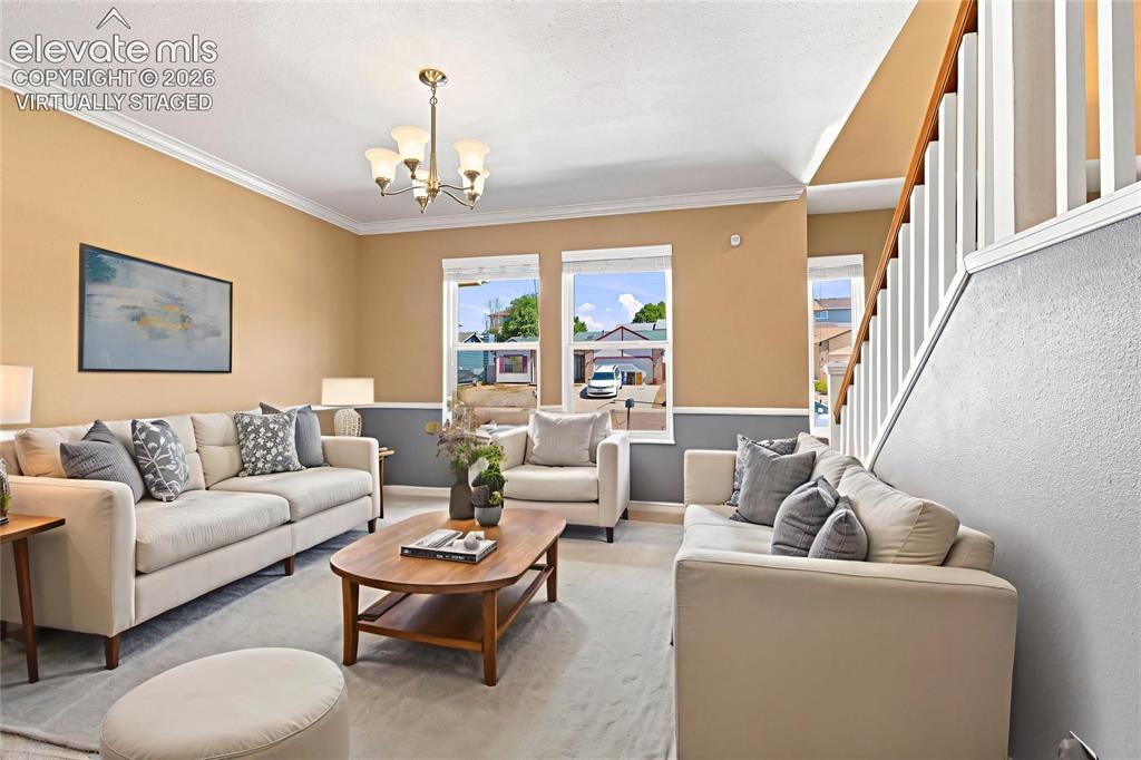 Image 8 of 49: Spacious living area featuring neutral walls, crown molding, a five-light c
