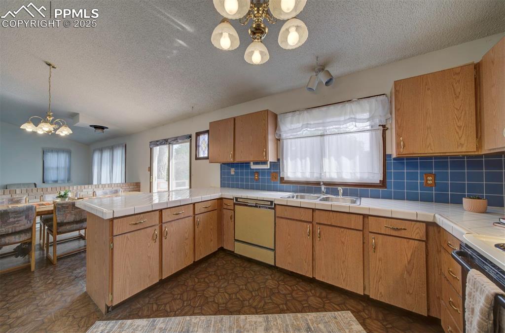 Image 18 of 50: The Kitchen features vinyl flooring, a pantry, wood cabinetry, tile counter