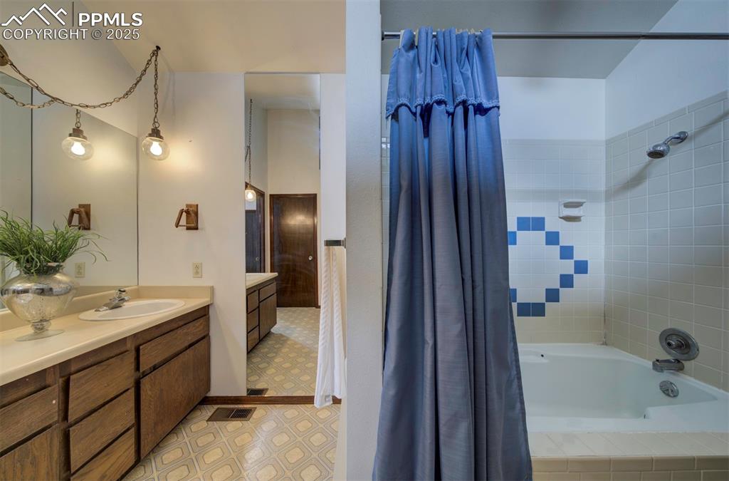 Image 25 of 50: Primary Bathroom with extended vanity, mirror, and tiled tub/shower.