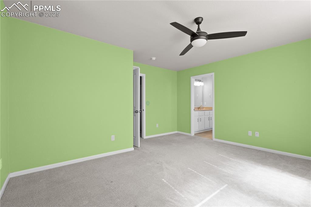 Image 14 of 26: Unfurnished bedroom with baseboards, ensuite bathroom, light carpet, and a 