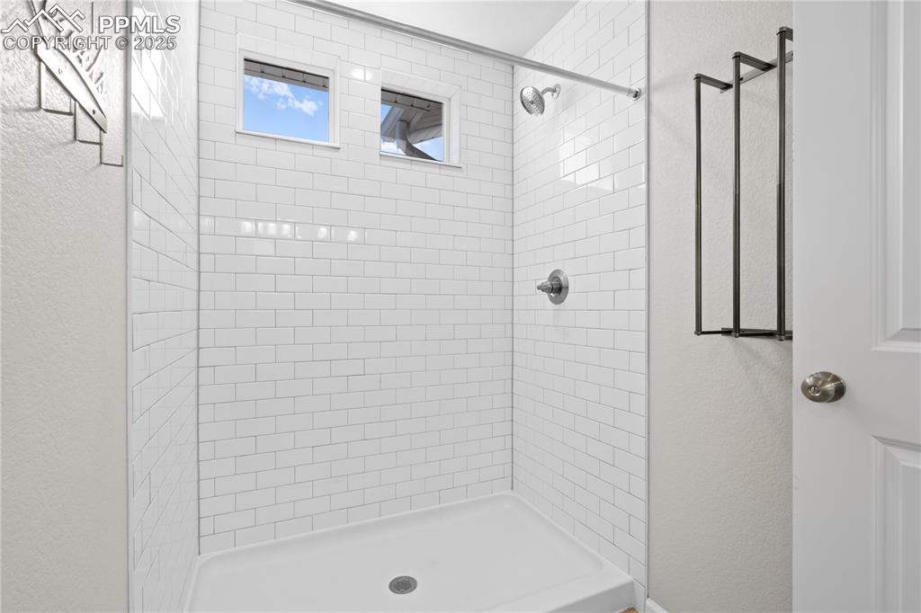 Image 16 of 26: Bathroom with a textured wall and a shower stall
