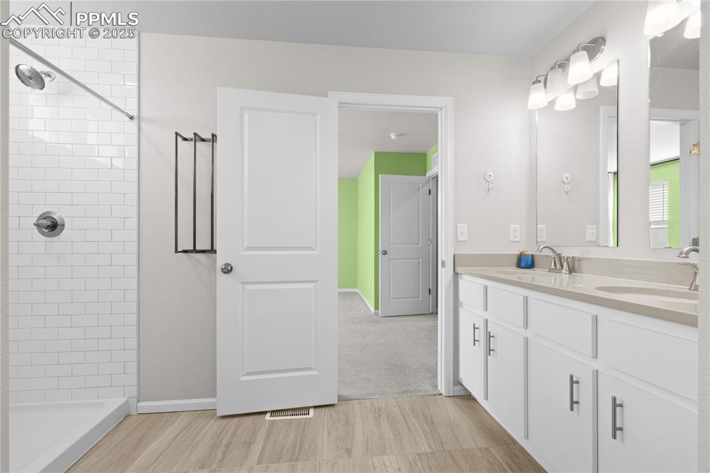 Image 17 of 26: Full bathroom with double vanity, a sink, wood finished floors, and a tile 