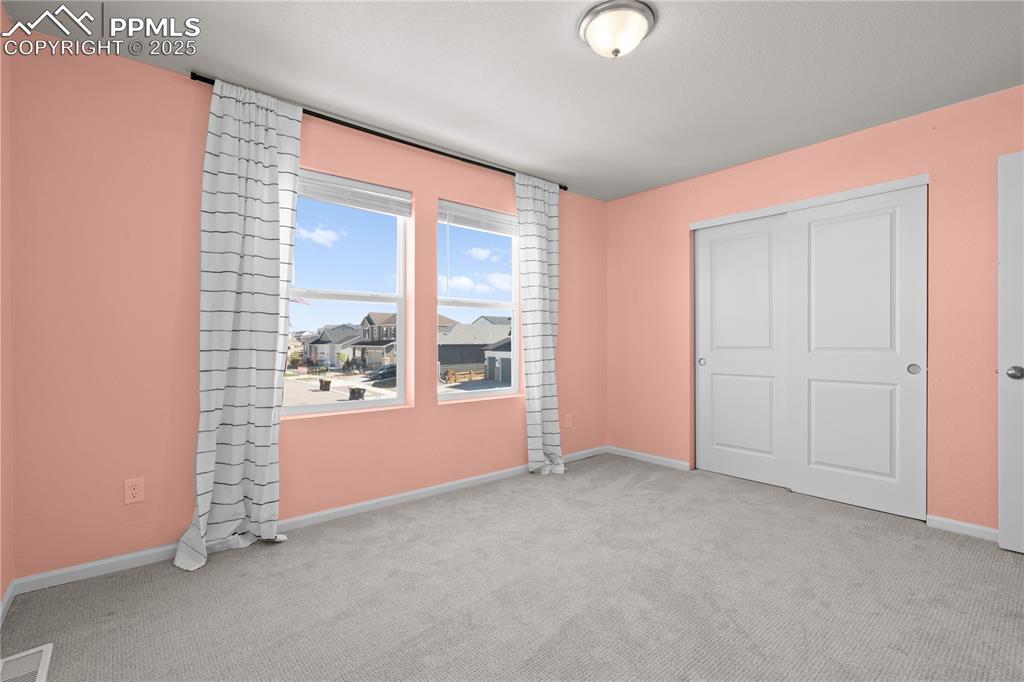 Image 23 of 26: Unfurnished bedroom featuring carpet floors, baseboards, a closet, and visi