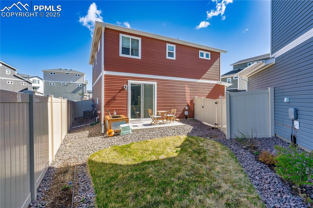 Image 26 of 26: Rear view of house with a fenced backyard, a patio, a lawn, and central AC