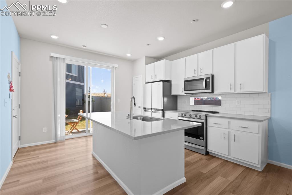 Image 4 of 26: Kitchen featuring baseboards, a sink, light wood finished floors, appliance
