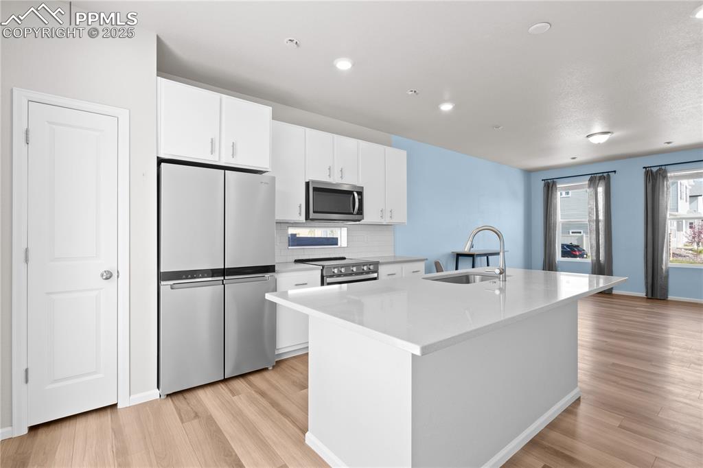 Image 5 of 26: Kitchen with white cabinets, stainless steel appliances, a sink, and light 