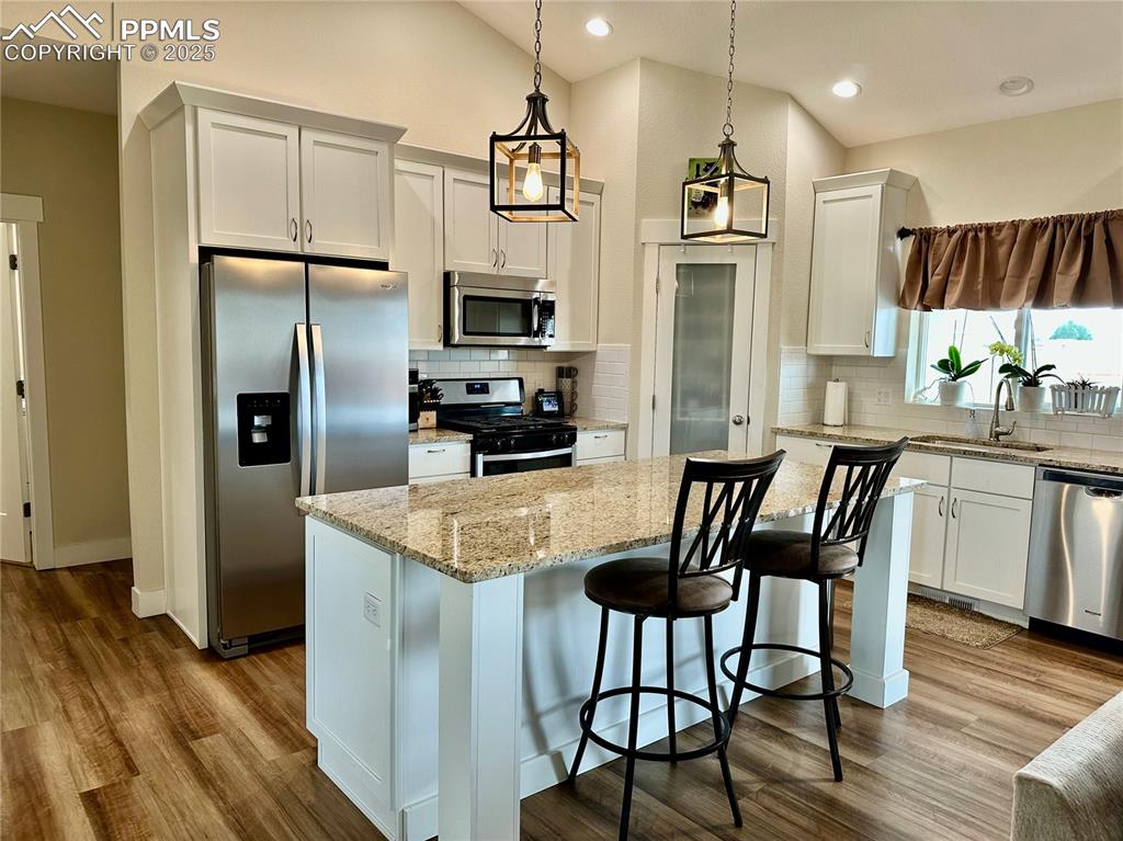 Image 11 of 38: Kitchen featuring stainless steel appliances, white cabinetry, light stone