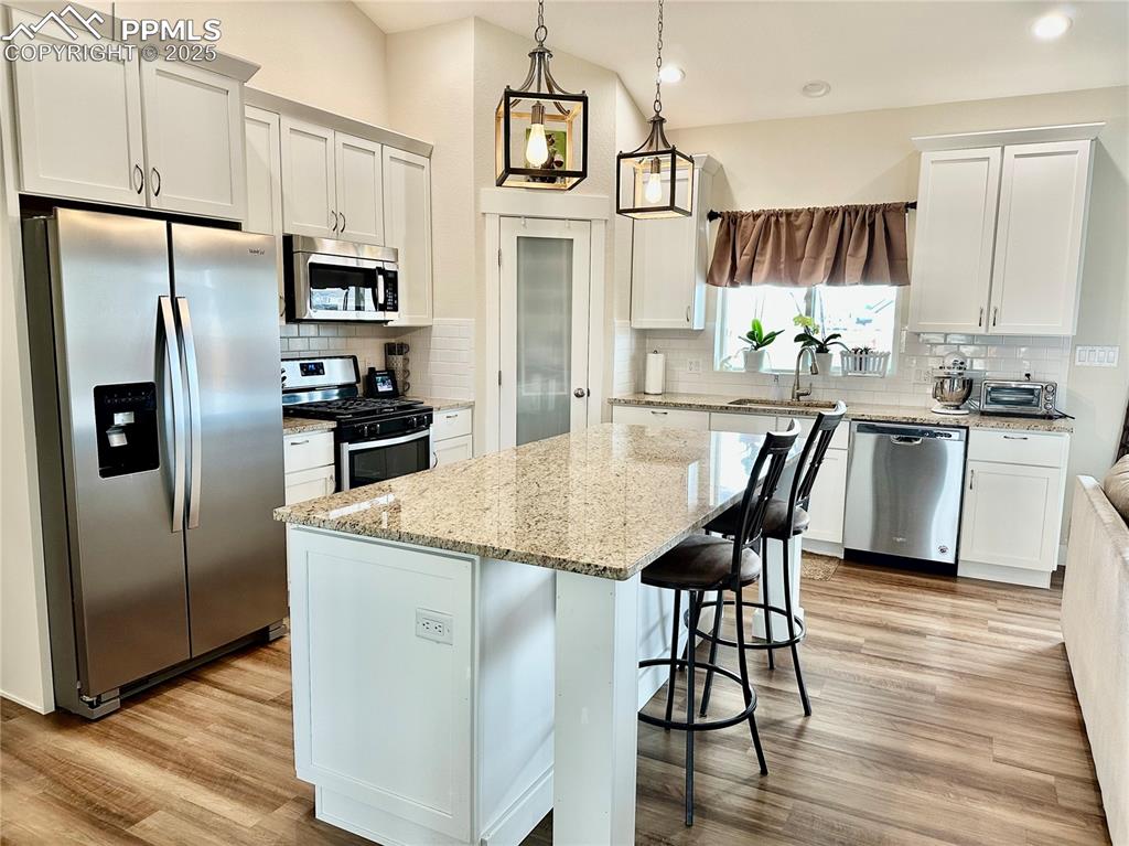 Image 12 of 38: Kitchen with stainless steel appliances, decorative backsplash, white cabin