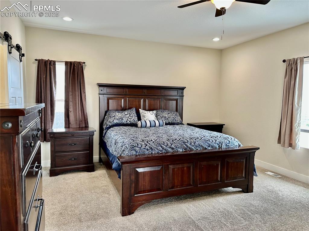 Image 13 of 38: Bedroom featuring light colored carpet, multiple windows, recessed lighting