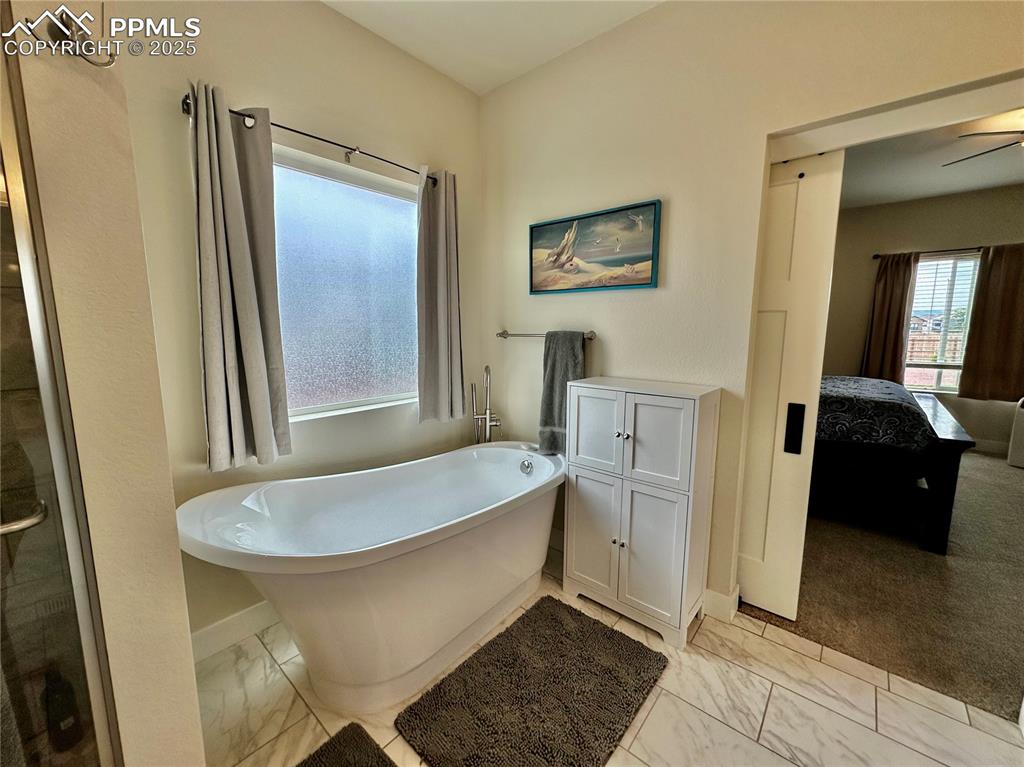Image 17 of 38: Bathroom featuring ensuite bathroom, a soaking tub, light marble finish flo