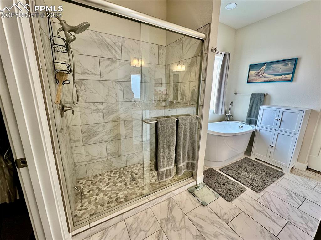 Image 18 of 38: Full bath featuring a freestanding bath, a shower stall, and marble finish