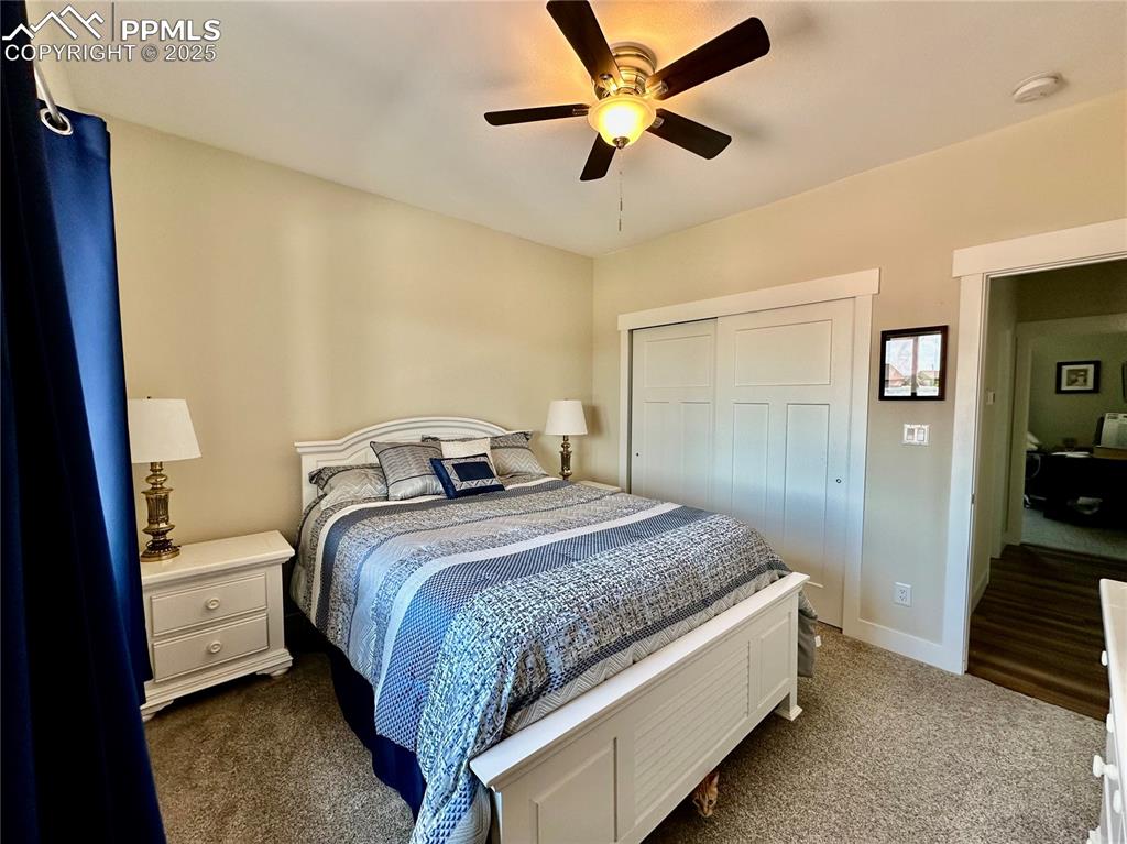 Image 22 of 38: Bedroom with a closet, dark colored carpet, and a ceiling fan
