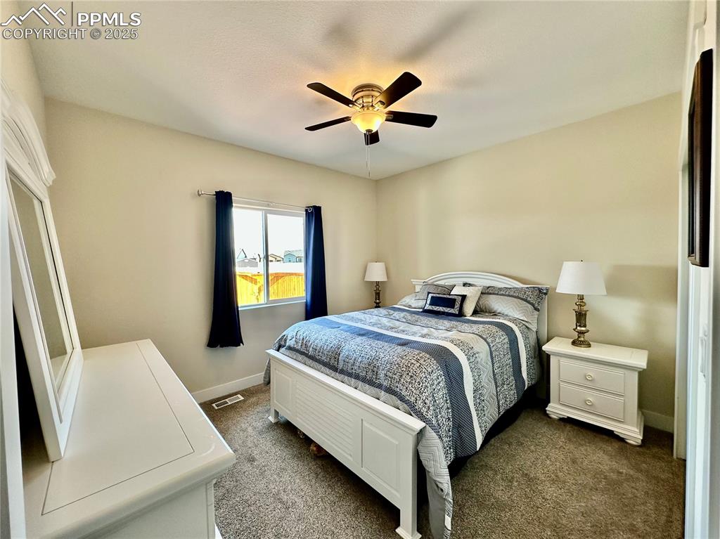 Image 23 of 38: Bedroom with dark carpet and ceiling fan