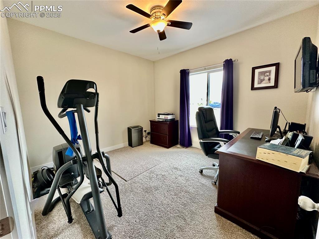 Image 25 of 38: Office area with light colored carpet and a ceiling fan