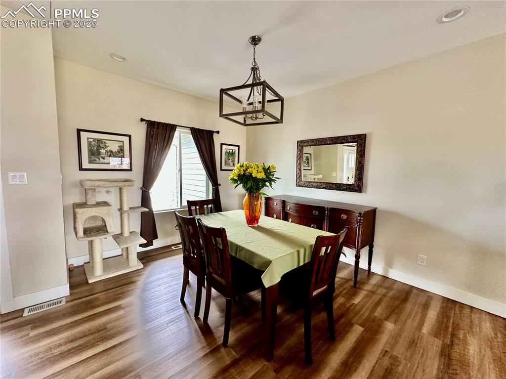 Image 6 of 38: Dining space with wood finished floors, a chandelier, and recessed lighting