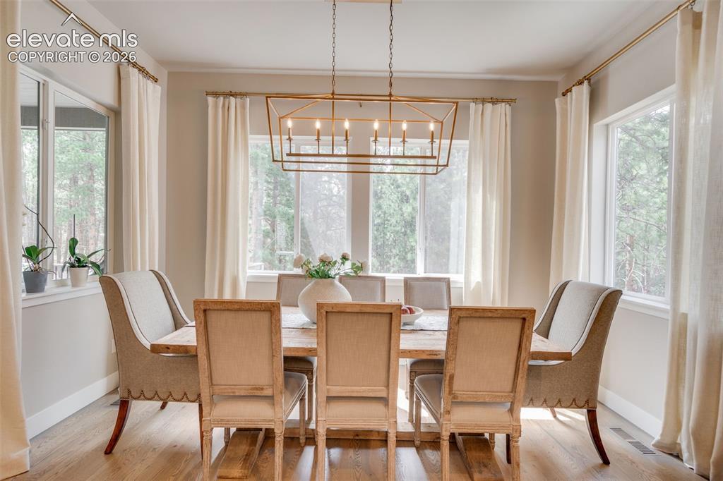 Image 15 of 48: dining room with wrap around windows over looking the woods