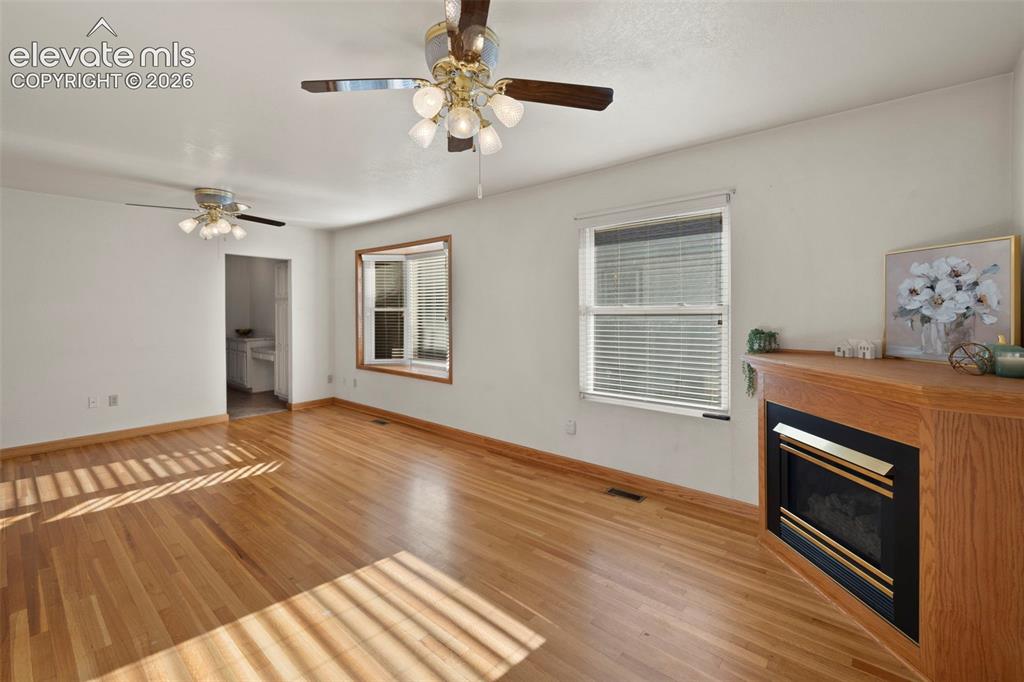 Image 10 of 44: Hardwood flooring throughout, featuring a corner fireplace with a wood mant