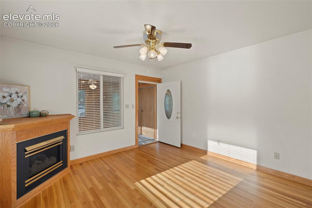 Image 13 of 44: Wood-finish flooring, built-in fireplace with wood mantel, white walls, cei