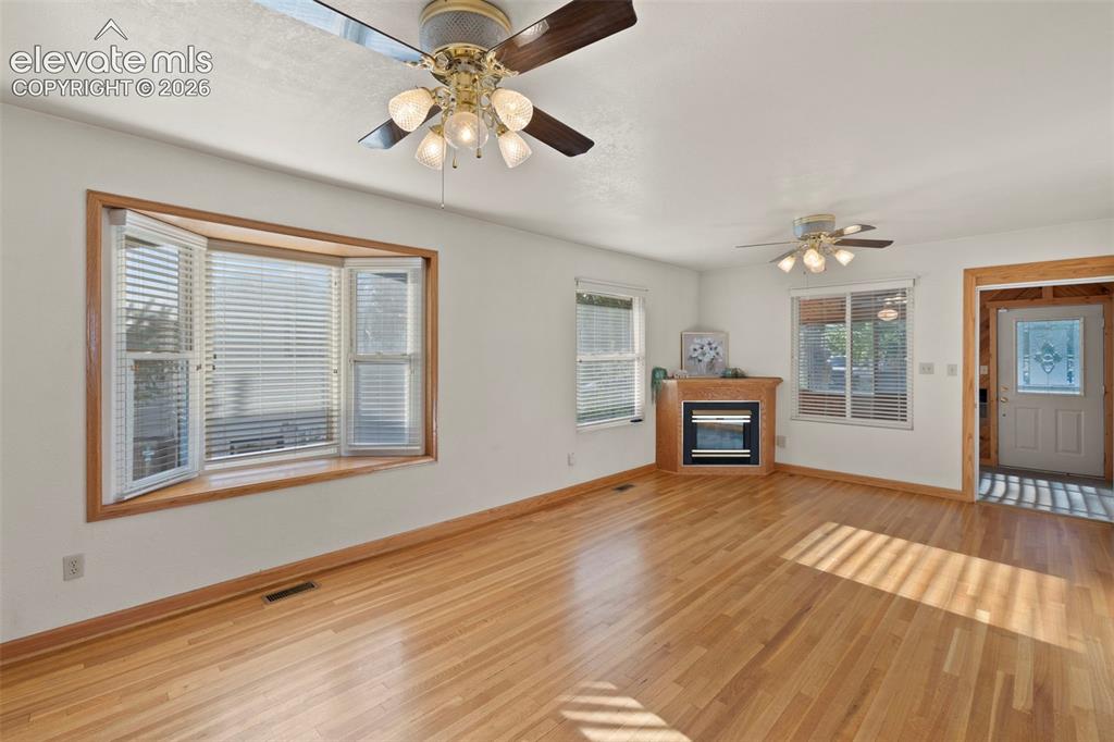 Image 15 of 44: Hardwood flooring throughout, bay window with wood trim, ceiling fans with 