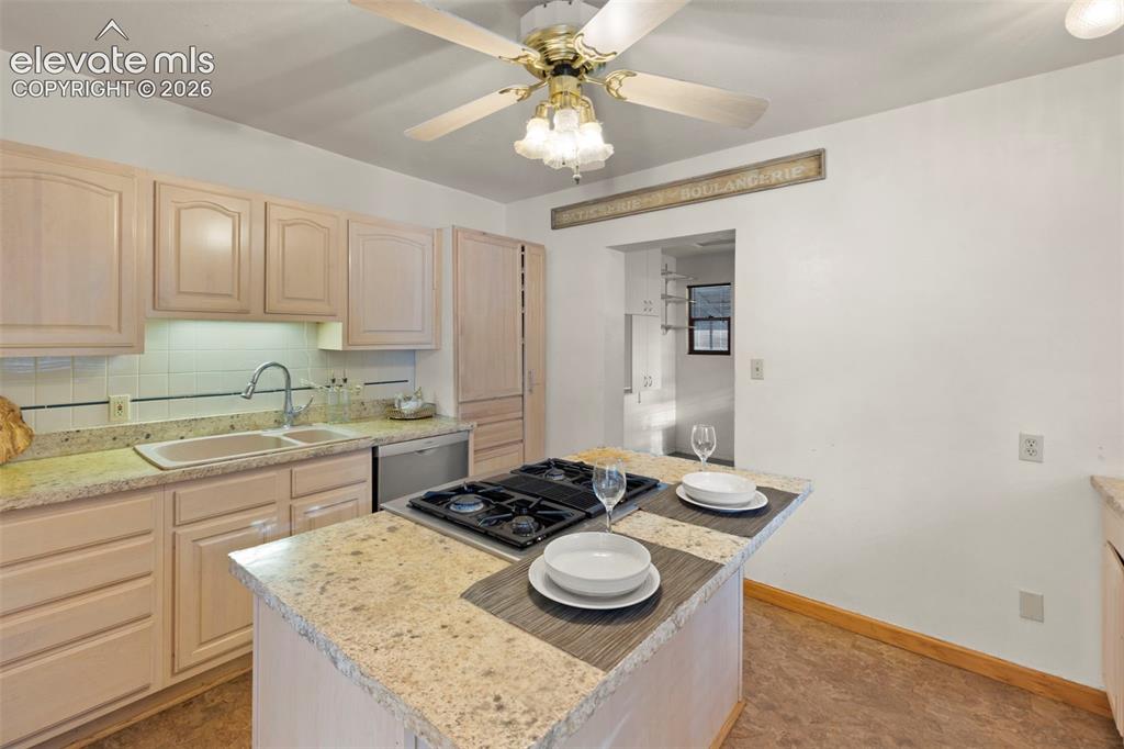 Image 19 of 44: Kitchen featuring a center island with built-in cooktop, light-toned cabine