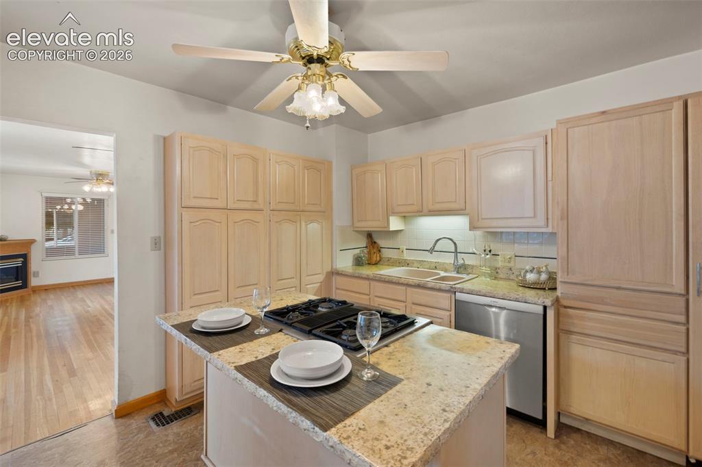 Image 20 of 44: Kitchen featuring a built-in gas cooktop on an island, light wood-finish ca