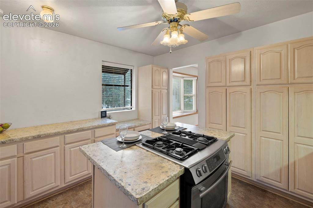Image 21 of 44: Kitchen featuring a center island with built-in gas range, extensive cabine