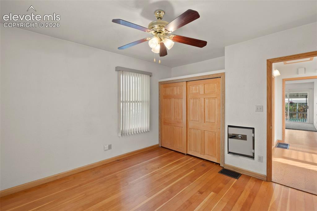 Image 25 of 44: Wood-finish flooring with light-toned baseboards, ceiling fan with light fi