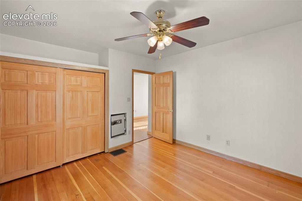 Image 26 of 44: Wood-finish flooring with baseboard trim, sliding paneled closet doors, and