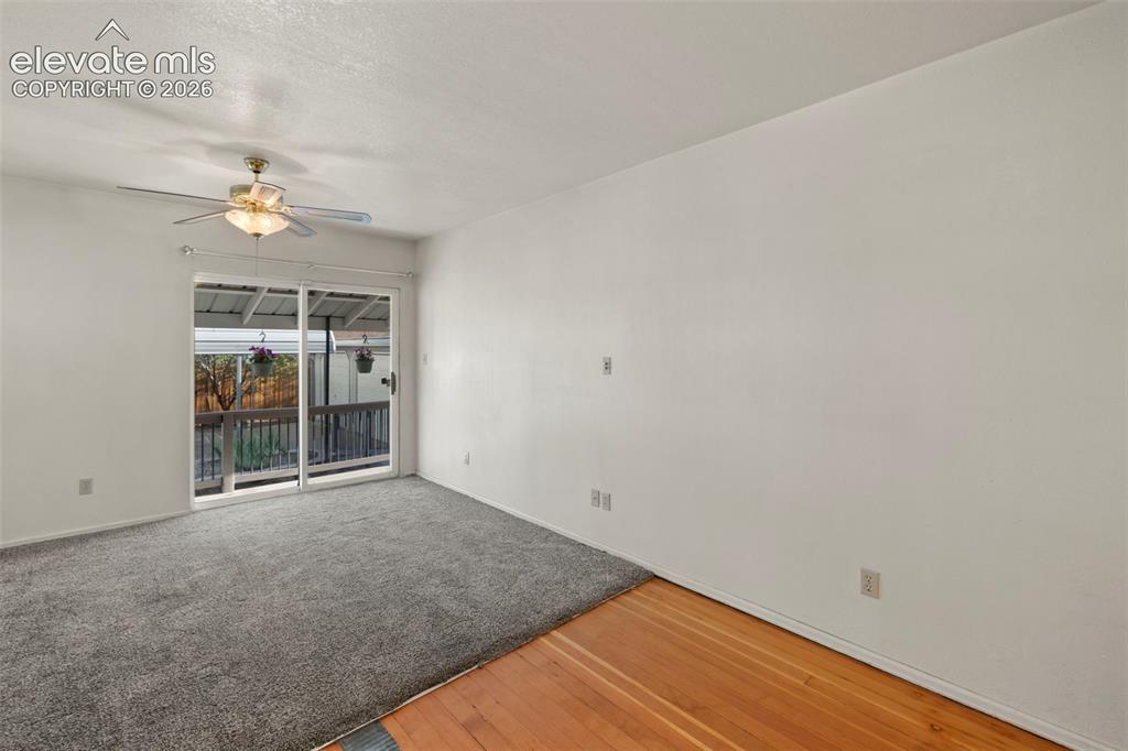 Image 32 of 44: Sliding glass door leading to an exterior deck, with a ceiling fan and over