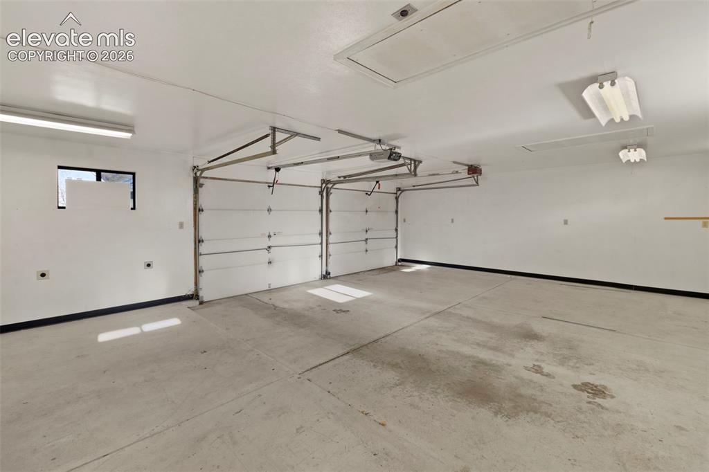 Image 41 of 44: Two overhead garage doors and a concrete floor