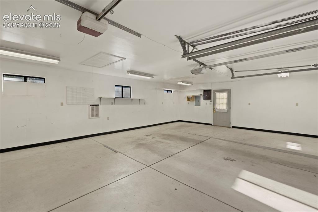 Image 43 of 44: Spacious garage featuring a concrete floor, multiple fluorescent light fixt