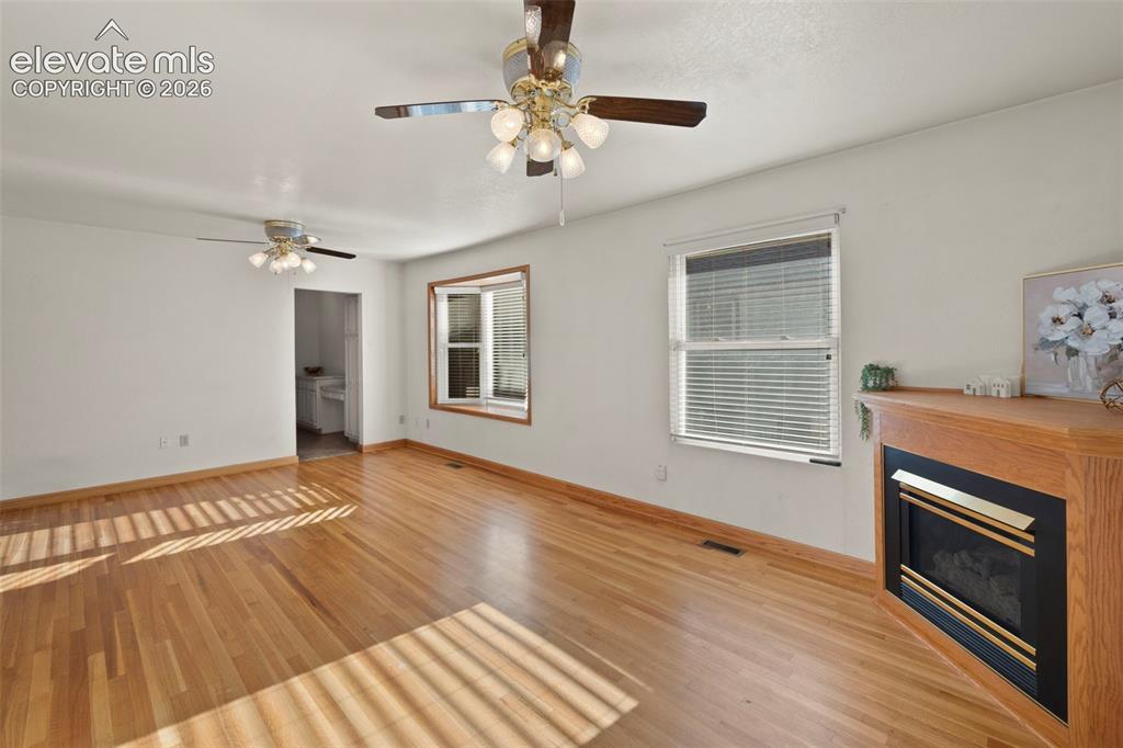 Image 9 of 44: Wood-finish flooring, recessed fireplace with wood surround, multiple windo