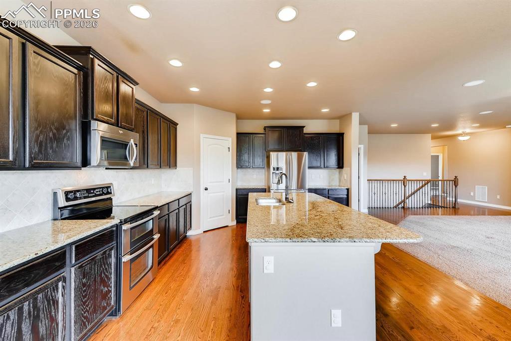 Image 10 of 28: Kitchen featuring backsplash, stainless steel appliances, light wood-style