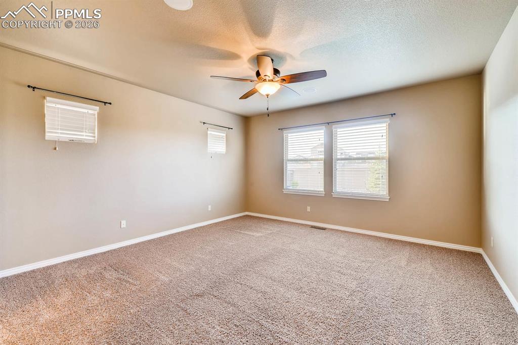 Image 13 of 28: Spare room featuring light colored carpet, ceiling fan, and a textured ceil