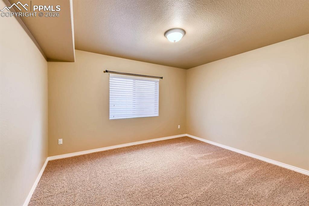 Image 23 of 28: Carpeted empty room with a textured ceiling and baseboards