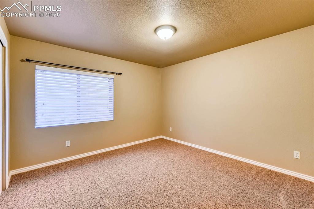 Image 24 of 28: Empty room with a textured ceiling and light carpet