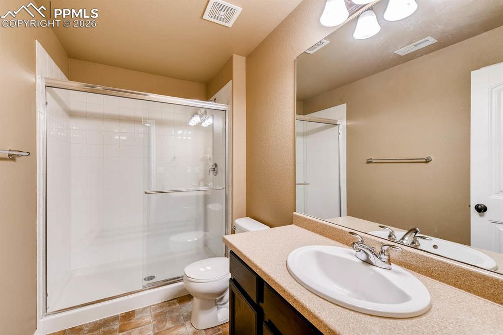 Image 25 of 28: Full bathroom featuring vanity, a shower stall, and stone finish flooring
