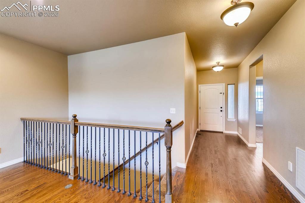Image 4 of 28: Hallway featuring wood finished floors, an upstairs landing, and a textured