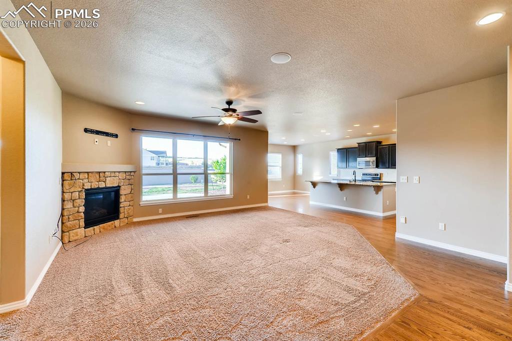 Image 5 of 28: Unfurnished living room with recessed lighting, a ceiling fan, a stone fire
