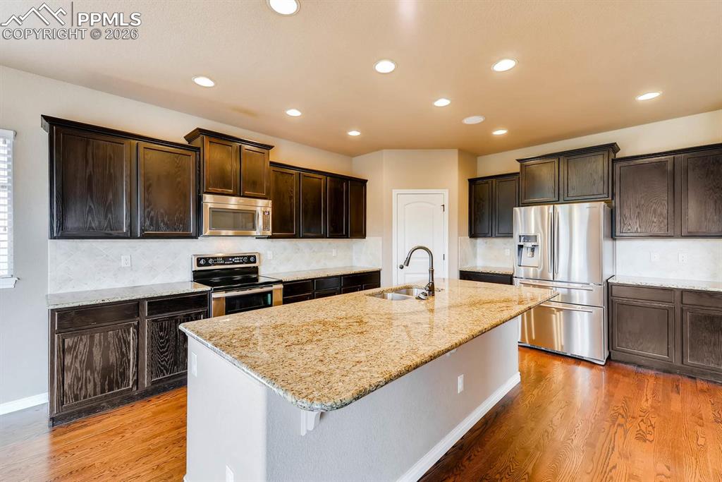 Image 8 of 28: Kitchen featuring stainless steel appliances, light stone countertops, ligh