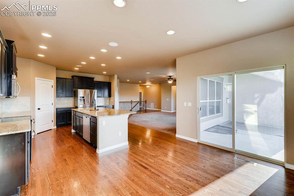 Image 9 of 28: Kitchen featuring light stone counters, open floor plan, an island with sin