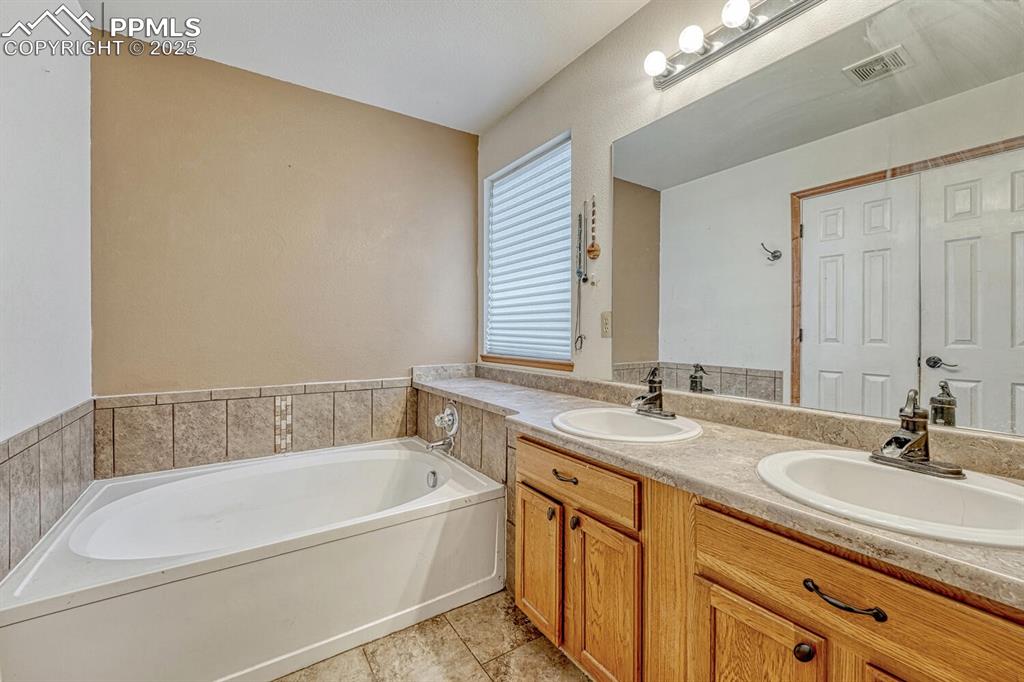 Image 18 of 47: Primary bathroom with double vanity and soaking tub