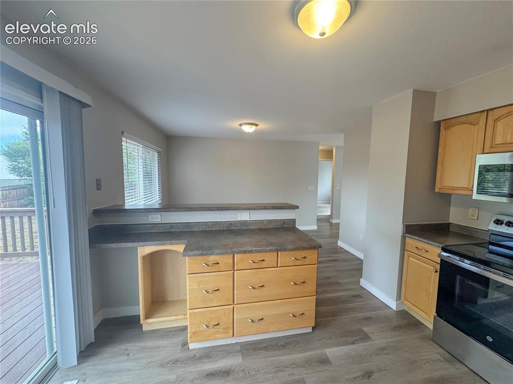 Image 15 of 42: Kitchen featuring a peninsula with solid-surface countertops, light wood-fi
