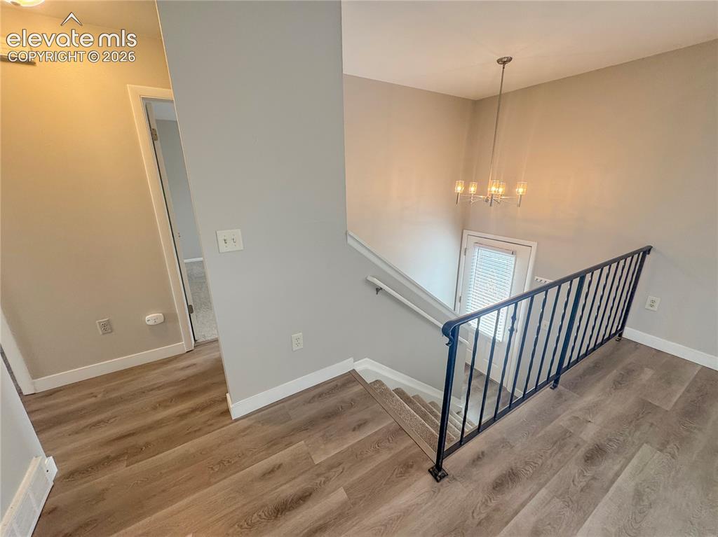 Image 16 of 42: Stairwell featuring wood-finish flooring, black metal railing, neutral wall