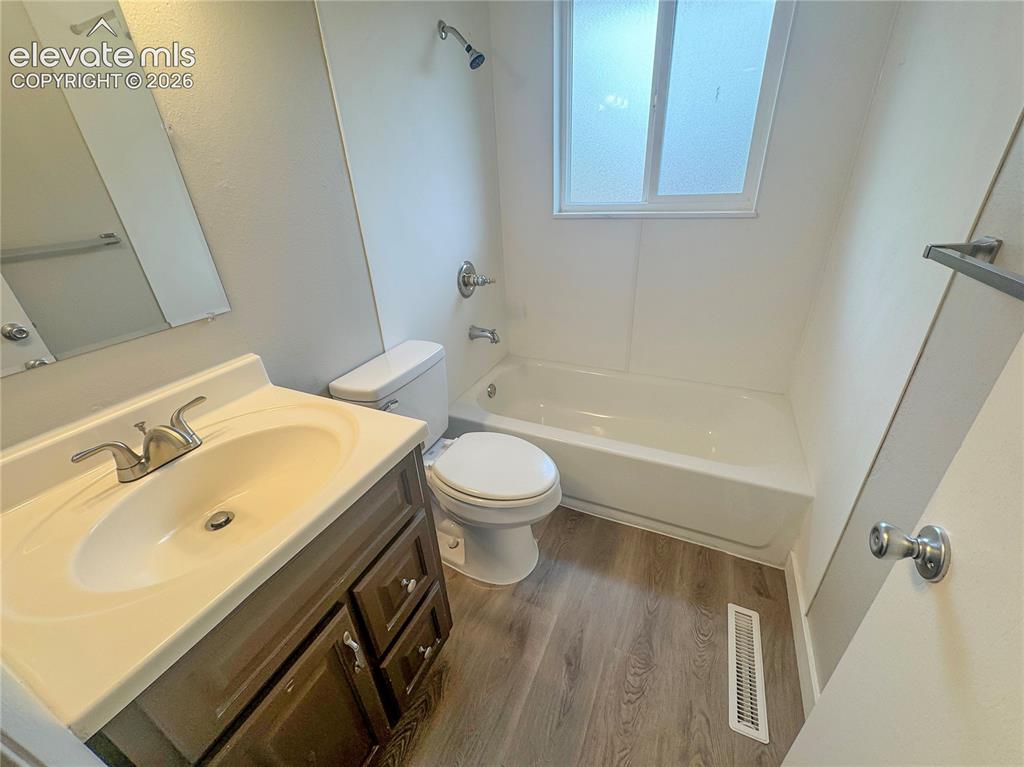 Image 19 of 42: Bathroom featuring a single-sink vanity with a molded countertop, wood-fini