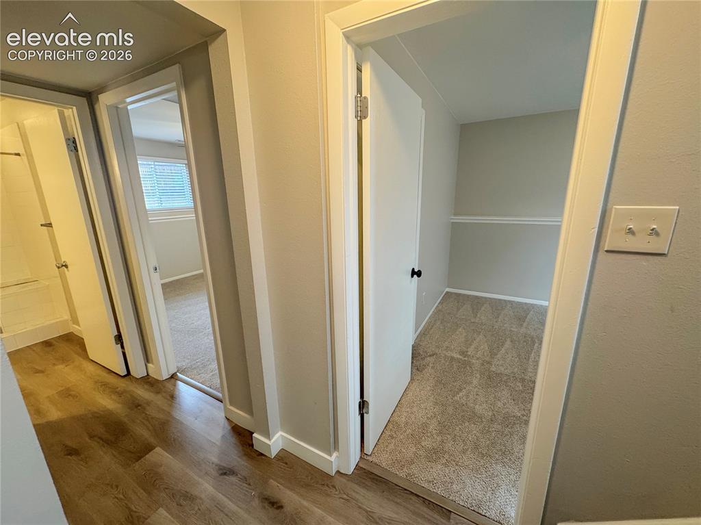 Image 21 of 42: Hallway featuring wood-finish flooring, carpeted flooring, and chair rail m