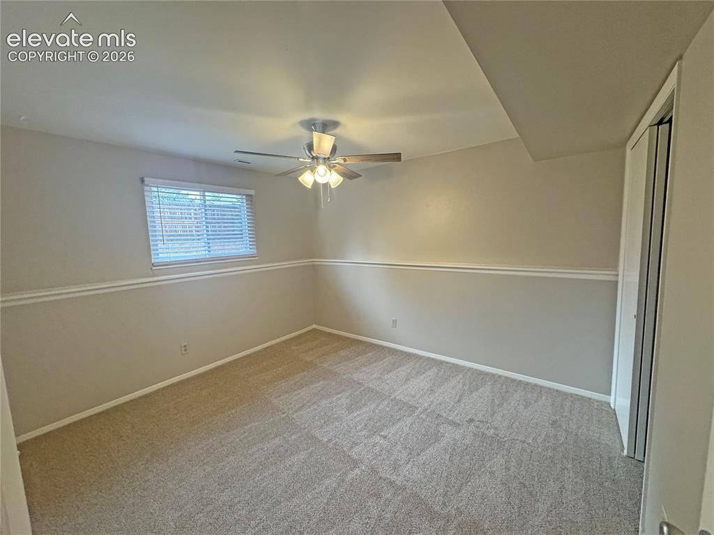 Image 24 of 42: Neutral carpeting, chair rail molding, multi-blade ceiling fan with integra