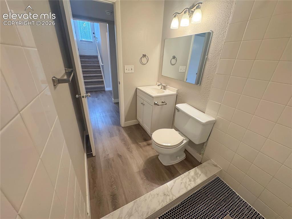 Image 26 of 42: Bathroom featuring wood-finish flooring, white vanity with integrated sink,