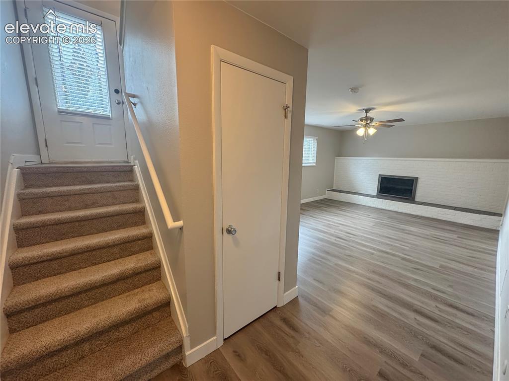 Image 27 of 42: Wood-finish flooring, white painted brick fireplace with hearth, carpeted s