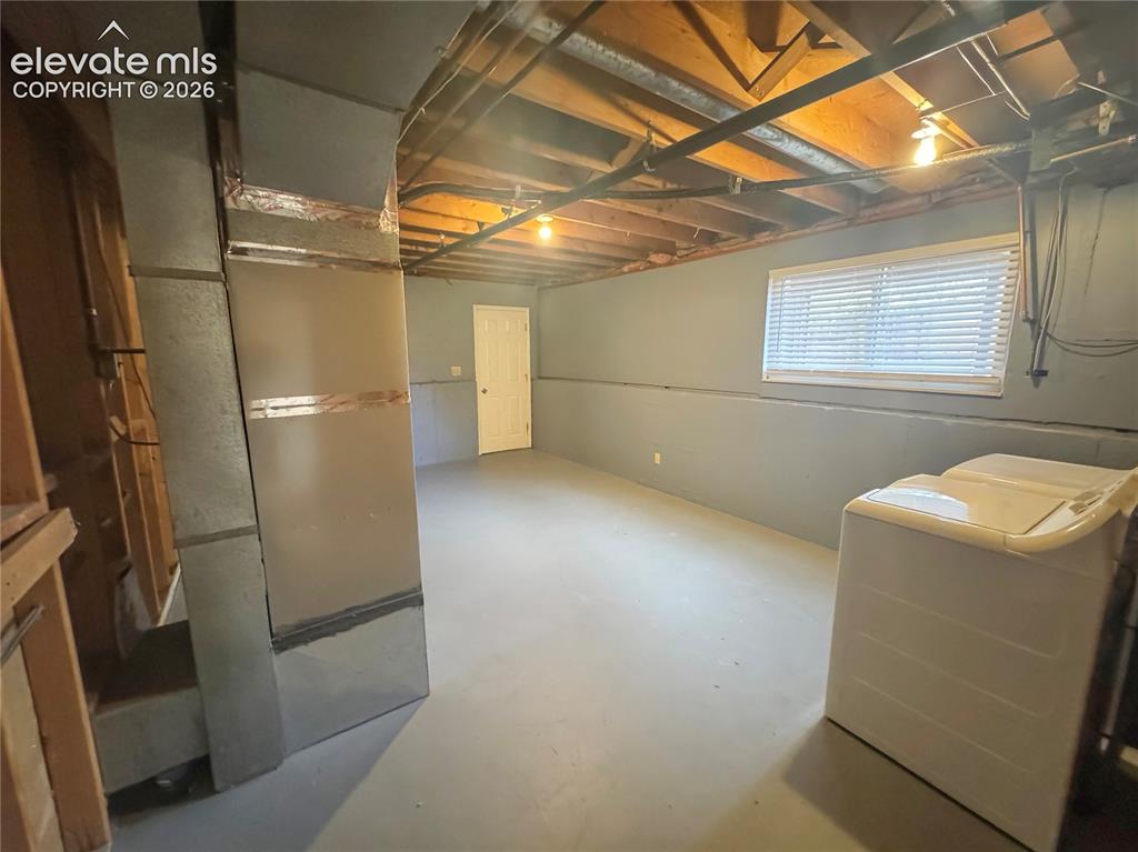 Image 31 of 42: Unfinished space featuring painted concrete walls, exposed ceiling joists,